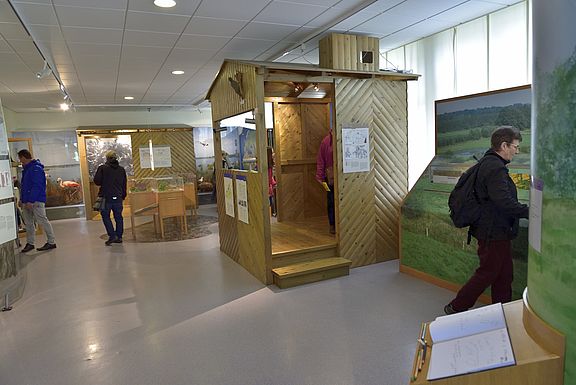 Menschen laufen durch die Ausstellung der Biologischen Station und schauen sich die dort aufgebauten Tafeln und Elemente an 