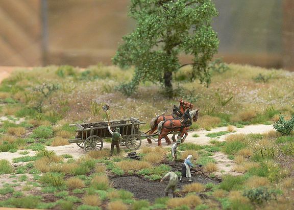 Ein Miniatur Modell von Feldarbeitern, die in einem Moor Torf abbauen, welcher dann durch eine von Pferden gezogene Kutsche abtransportiert wird